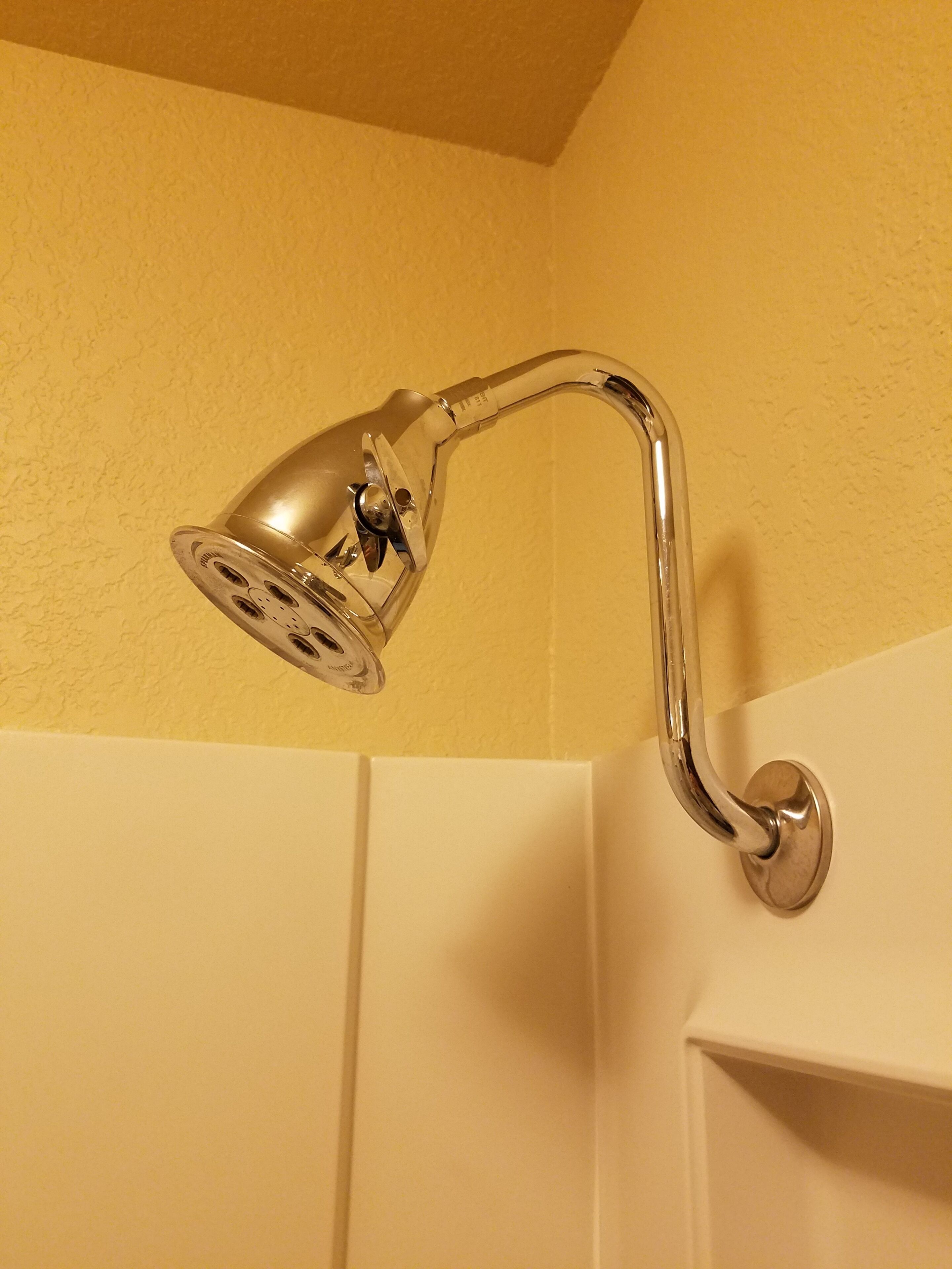 A corner-mounted showerhead with a curved arm and a round base.