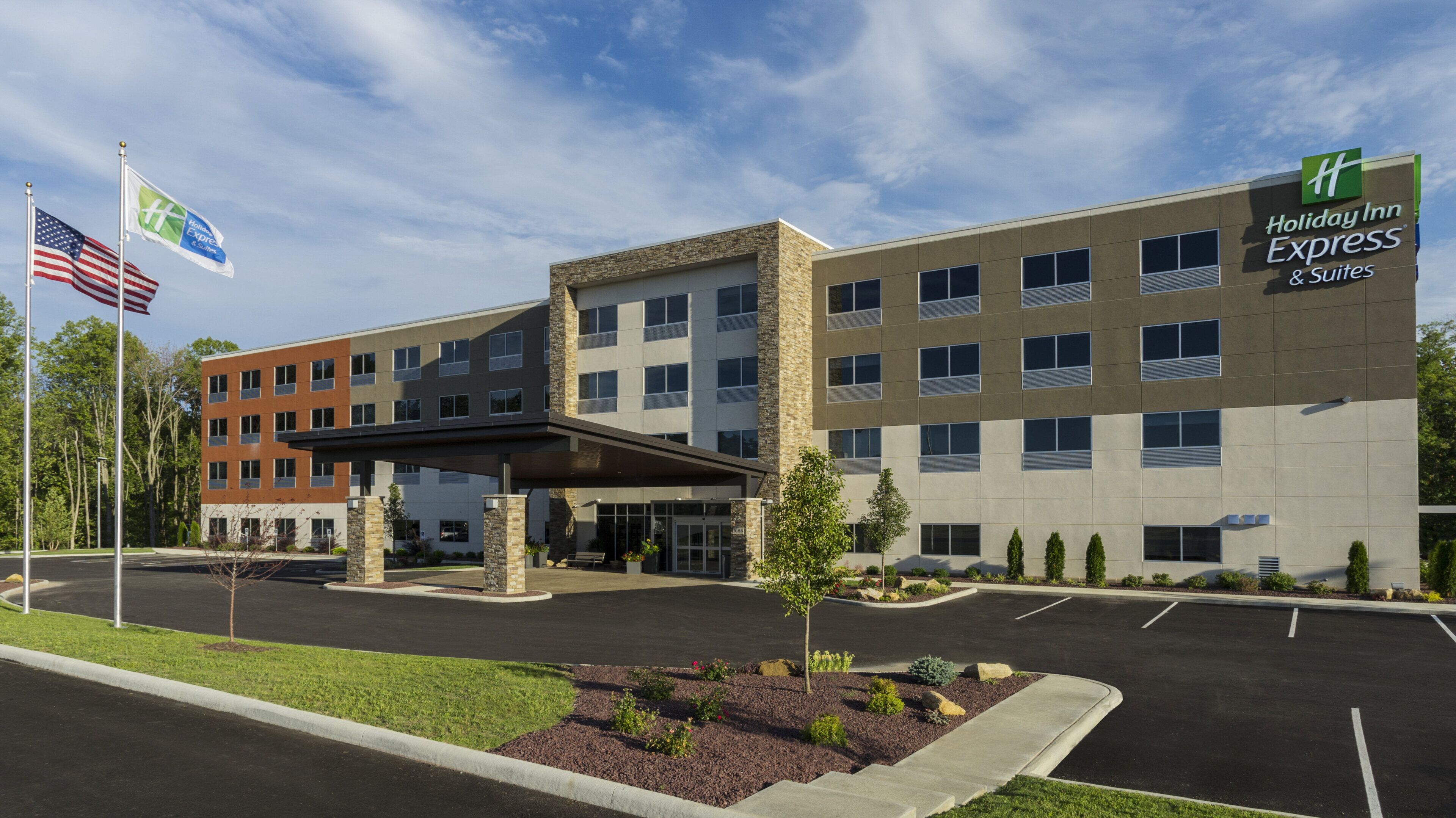 A Holiday Inn Express building with a covered entrance, parking lot, and landscaped area.