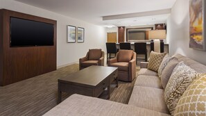 Een moderne woonkamer met een flatscreen televisie, twee fauteuils, een bank en een salontafel.