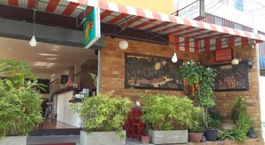 Un restaurant à la façade en briques, doté d’une terrasse et agrémenté de plantes en pot.