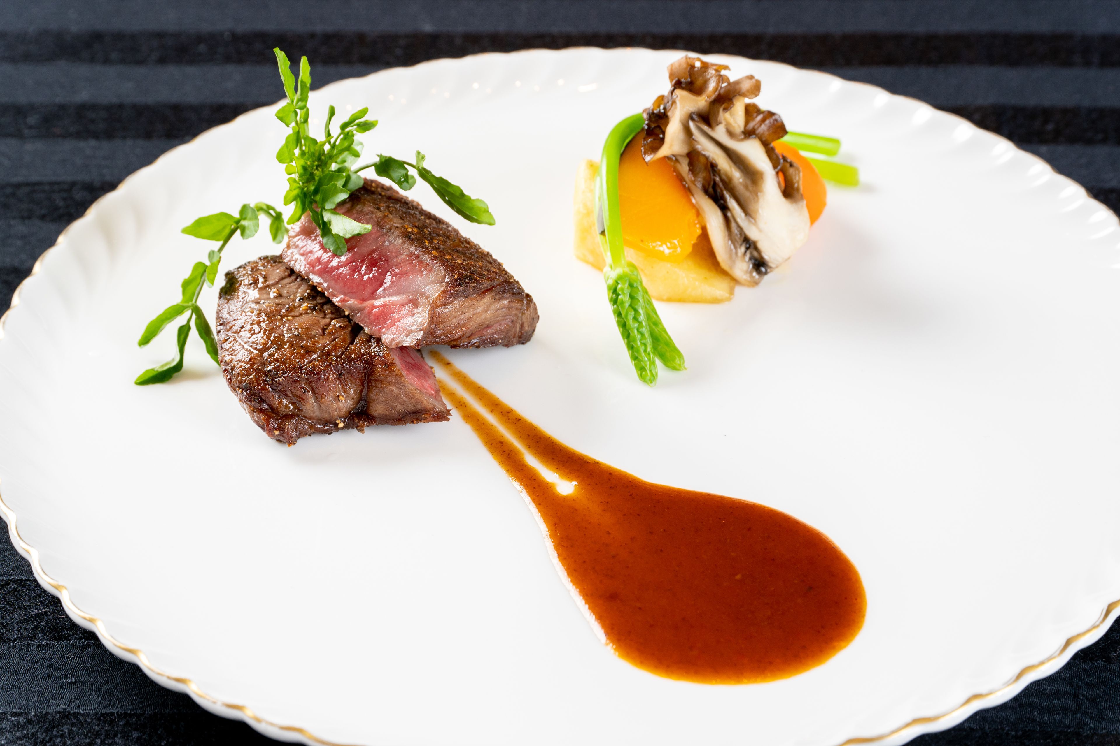 A white plate with a steak, mushrooms, and a sauce.