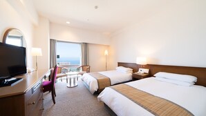 A hotel room with two beds, a desk with a TV, a chair, and a view of the ocean. - Hotel Terrace The Square Hitachi (Hitachi)