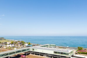 A modern building with a glass facade overlooking a coastal area. - Hotel Terrace The Square Hitachi (Hitachi)