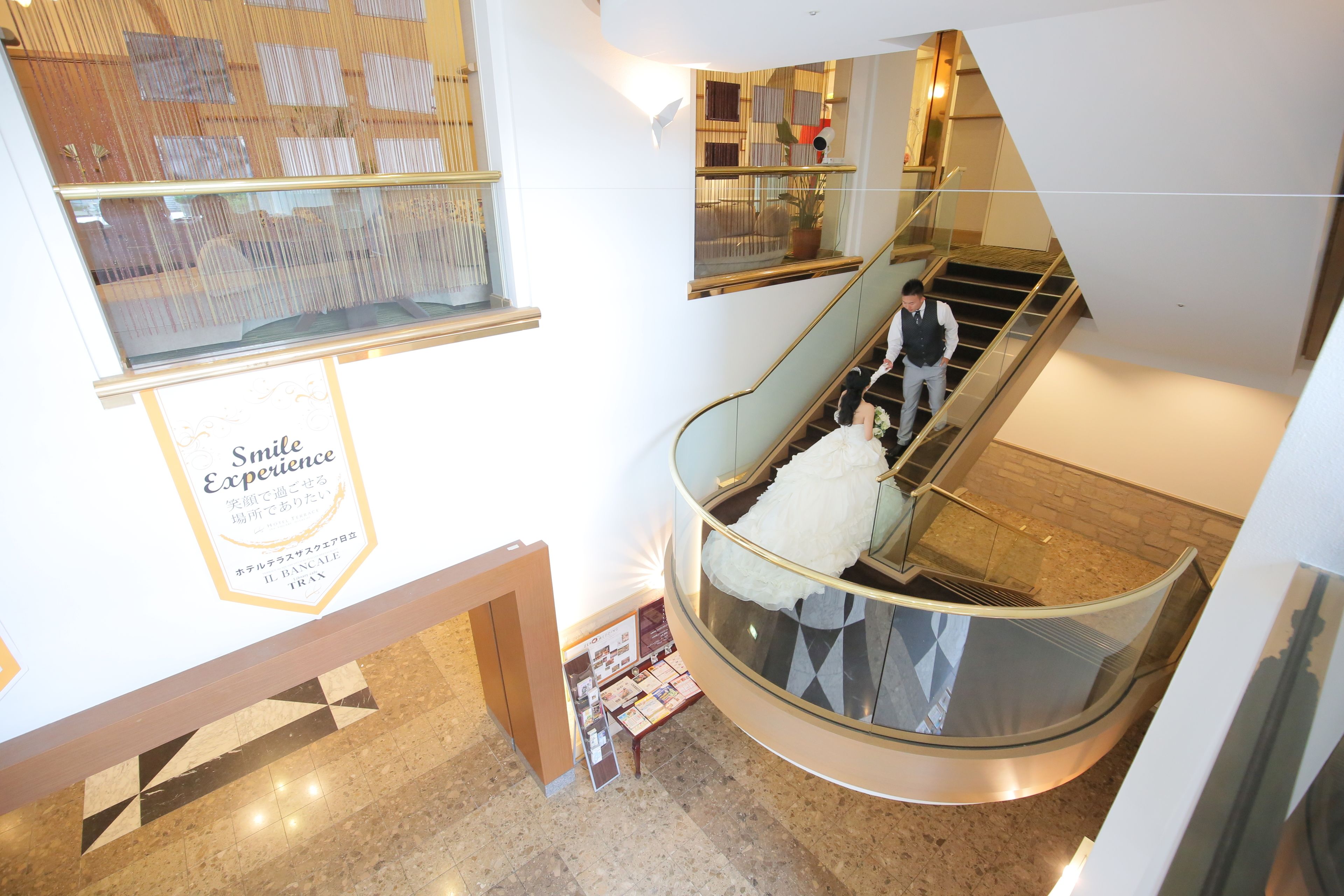 Una escalera de caracol con un objeto blanco y esponjoso, barandilla de cristal y un letrero con texto en japonés.