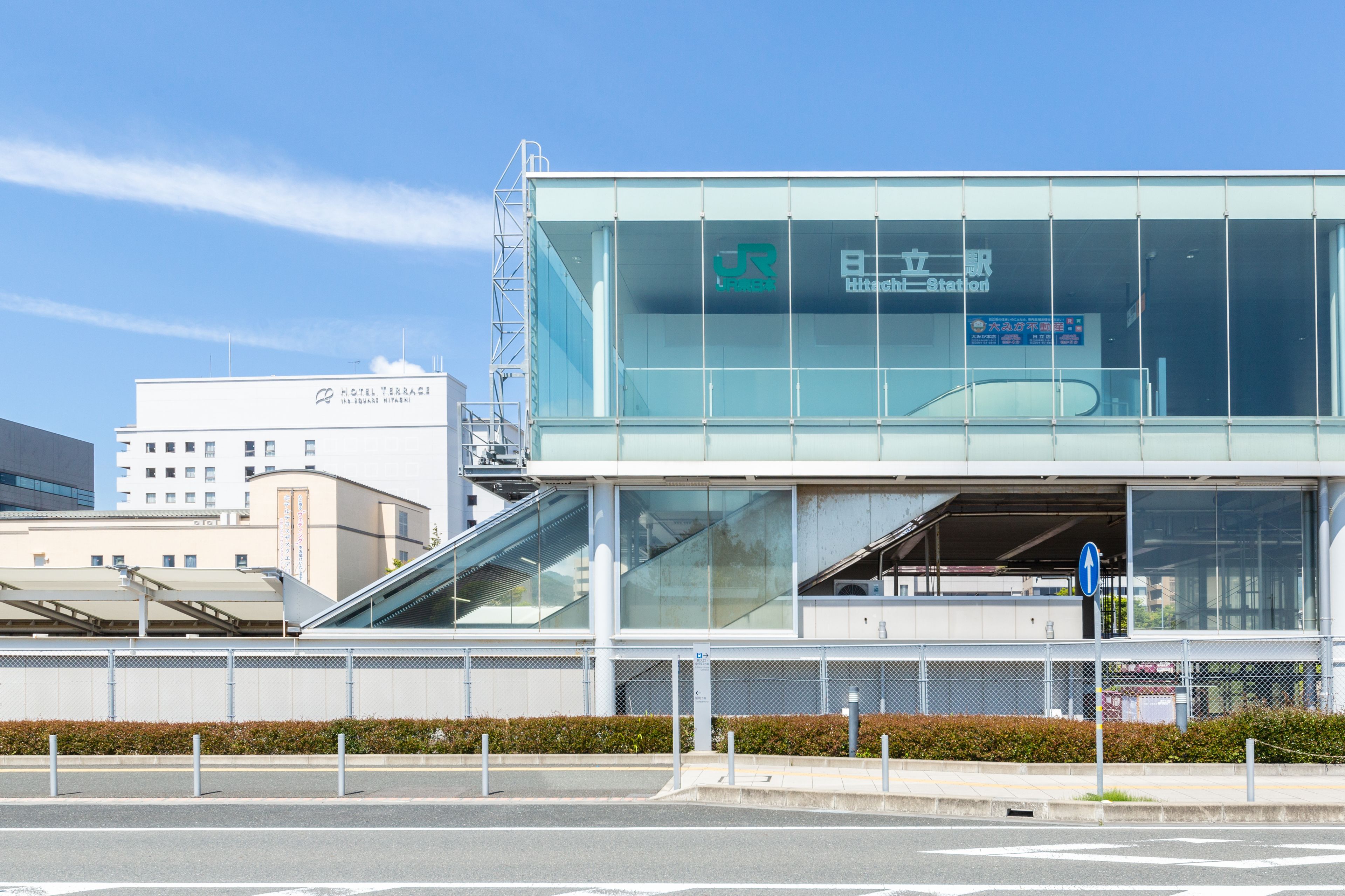 A modern hotel with a glass facade, an outdoor staircase, and a clear blue sky.