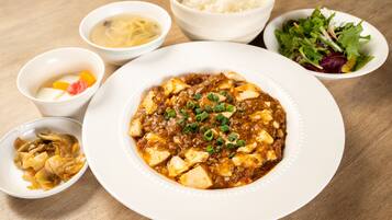 A table with various dishes including a bowl of soup, a plate of tofu, and a salad.