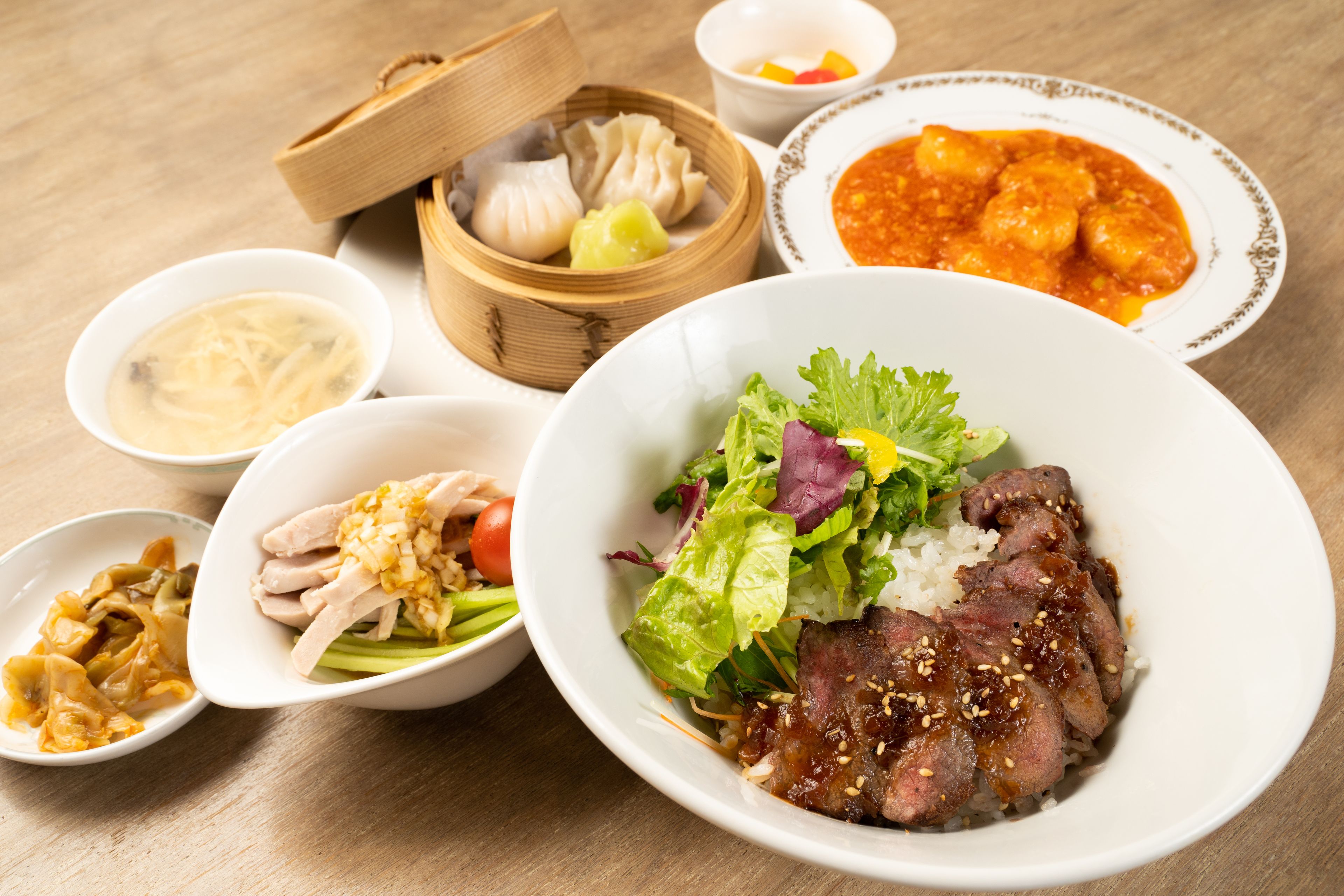 Variedad de platos, incluyendo dumplings, un tazón de sopa y una porción de carne con arroz y verduras.