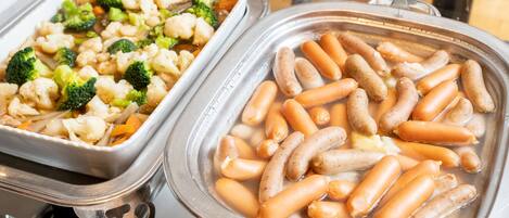 Dos dispensadores de comida con diversos platos, incluyendo salchichas y verduras.