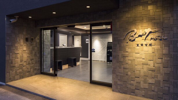A modern hotel entrance with a brick wall and glass doors leading to a reception area. - Tokyo Ariake Bay Hotel (Tokyo)