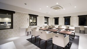 A modern conference room with white chairs and tables, large windows, and a visible bathroom area. - Tokyo Ariake Bay Hotel (Tokyo)