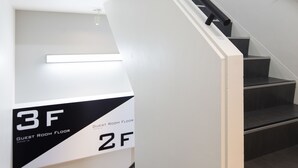 A modern staircase with black handrails and a white wall. There are signs indicating the 2nd and 3rd floors, and a guest room floor. - Tokyo Ariake Bay Hotel (Tokyo)