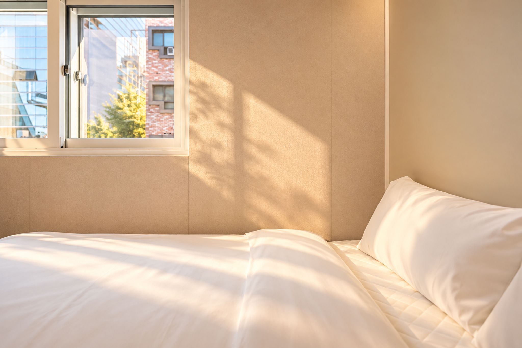 Une chambre à coucher avec un lit, une fenêtre et une vue sur les bâtiments environnants.