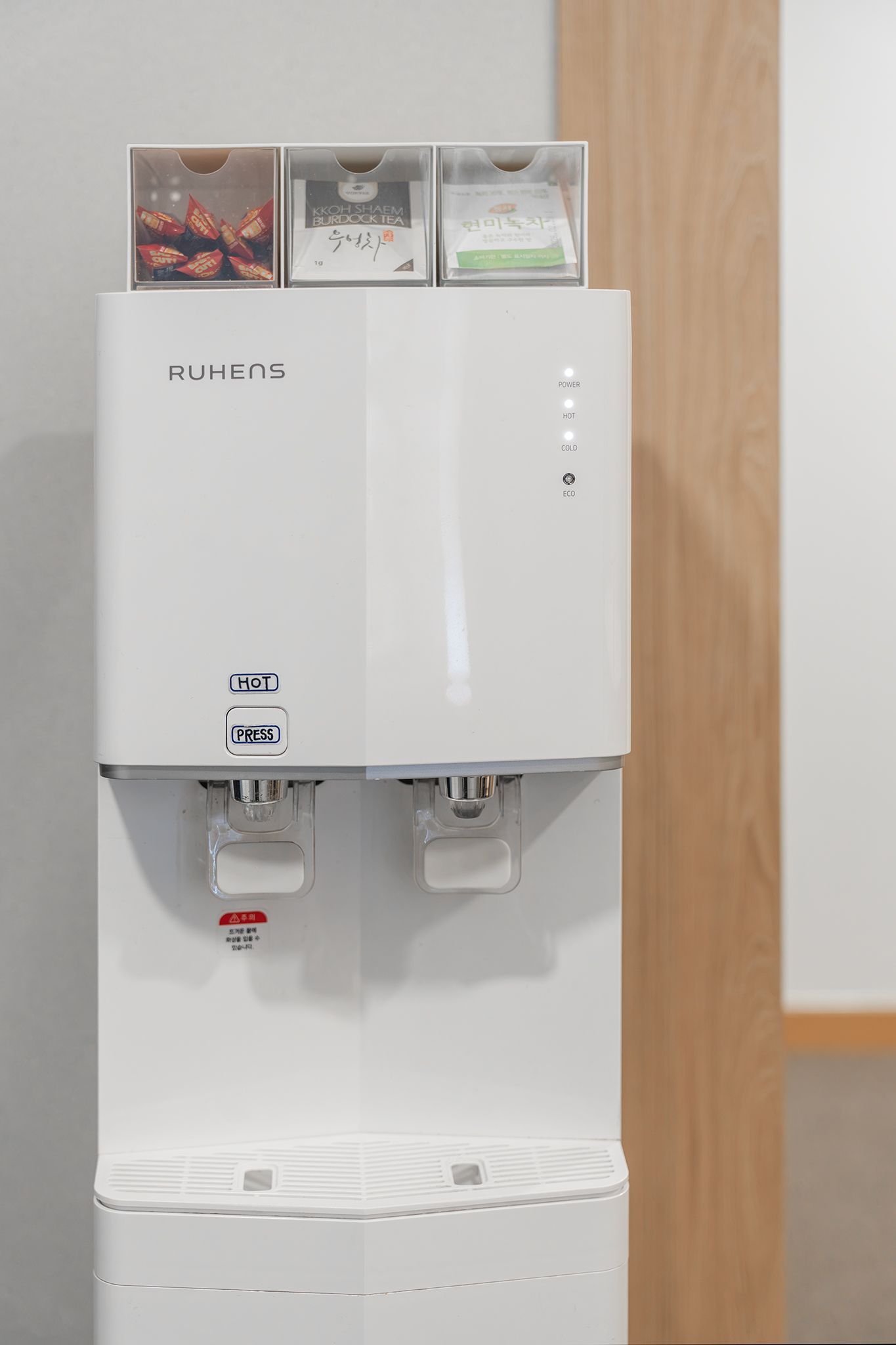 A Ruens branded water dispenser with hot, cold, and eco settings, and a power button.