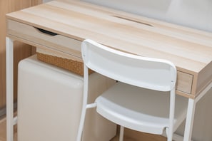 A white chair with a curved backrest and a wooden desk with a drawer.