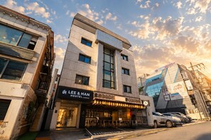A modern building with a restaurant named 'LEE & HAN HOSTEL INNANCHAM' on the ground floor.