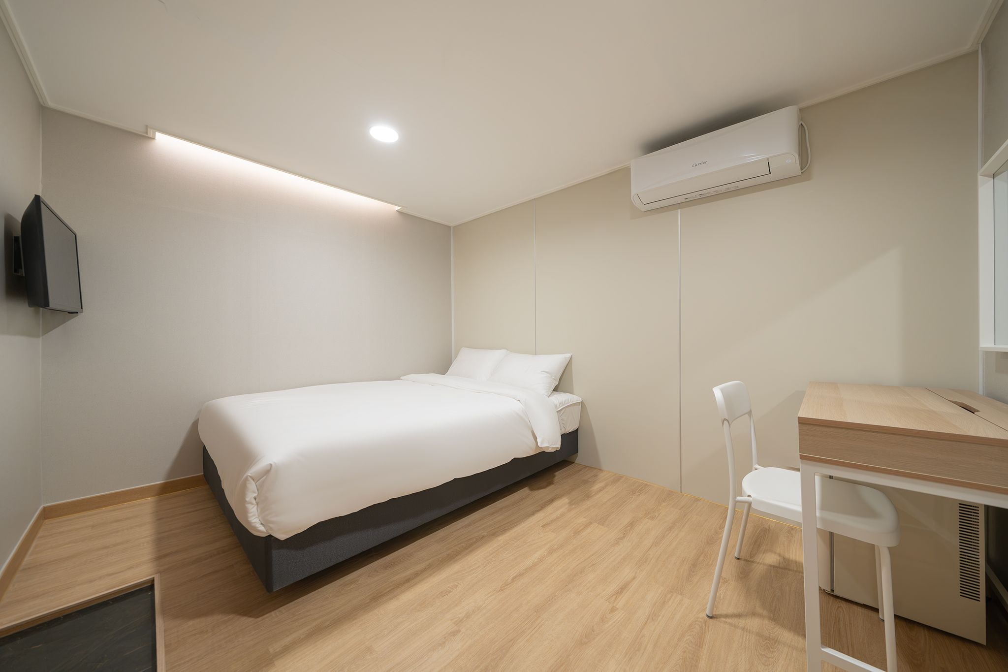 A modern bedroom with a bed, a desk, and a chair.