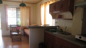 Una cocina compacta con comedor, que incluye una pequeña isla, armarios de madera y piso de baldosas.