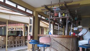 Zona de bar con taburete central, mostrador y área de asientos con taburetes.