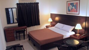 A hotel room with a bed, two bedside lamps, a desk with a chair, a small round table with a chair, a mirror, and a painting on the wall. - Perhentian Tropicana Inn (Pulau Perhentian Kecil)