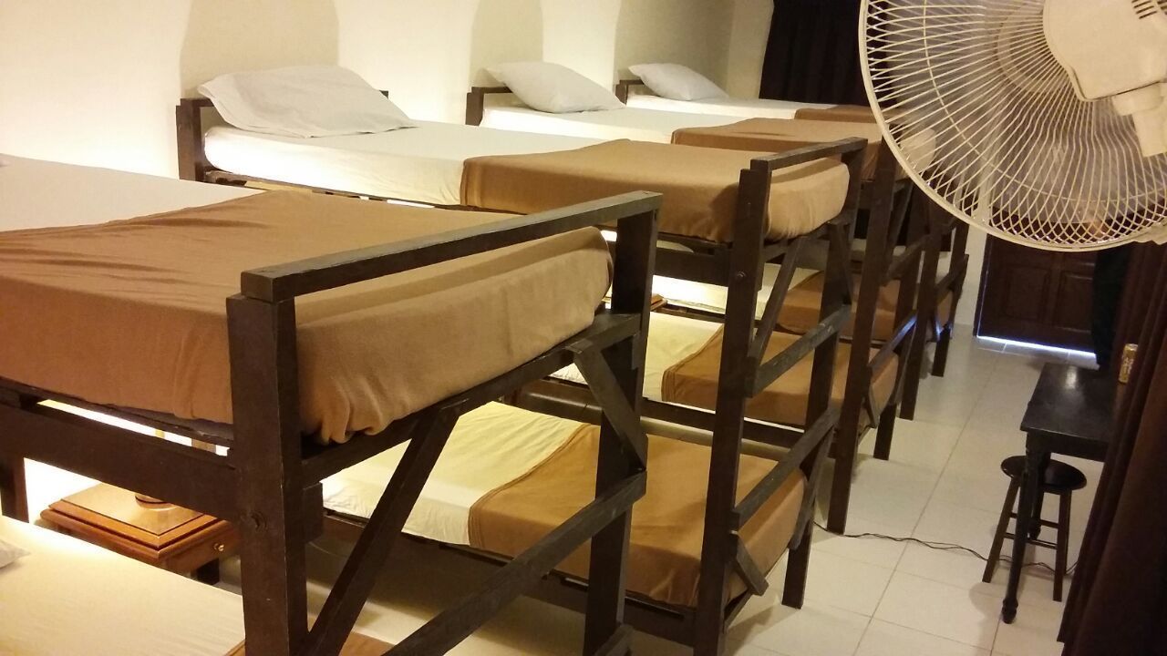 Habitación tipo dormitorio con literas, un ventilador y una mesita.