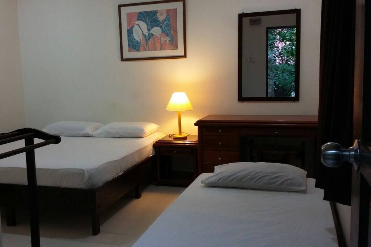 Ein Hotelzimmer mit Bett, Nachttisch mit Lampe, Kommode und Spiegel.