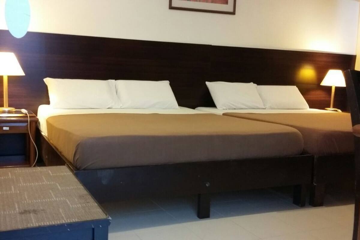 Ein Doppelbett mit zwei Kissen, ein Nachttisch mit Lampe und ein Sessel.