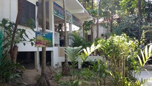 A building with a covered outdoor area surrounded by various plants and trees. - Perhentian Tropicana Inn (Pulau Perhentian Kecil)