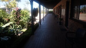 A covered walkway with brick walls, potted plants, and outdoor seating. - Country Ayr Motel (Ayr)
