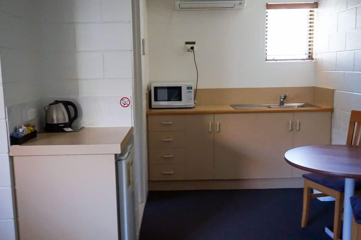 Cocina compacta con microondas, lavabo y hervidor sobre la encimera.