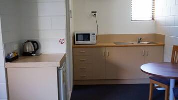 A compact kitchen with a microwave, sink, and a kettle on the counter.