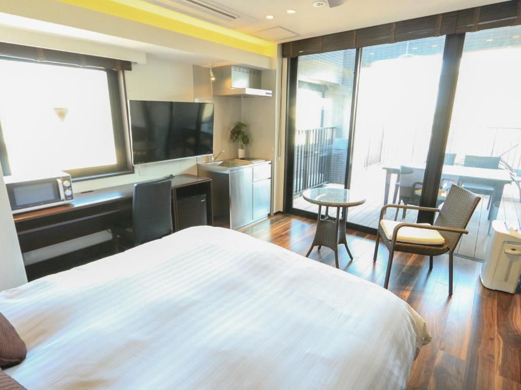 Ein Hotelzimmer mit Bett, Schreibtisch, Stuhl, einem kleinen Tisch und einem Balkon mit Blick.