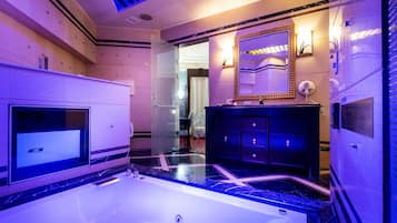 A modern bathroom with a large bathtub, a vanity with a mirror, and a shower area.