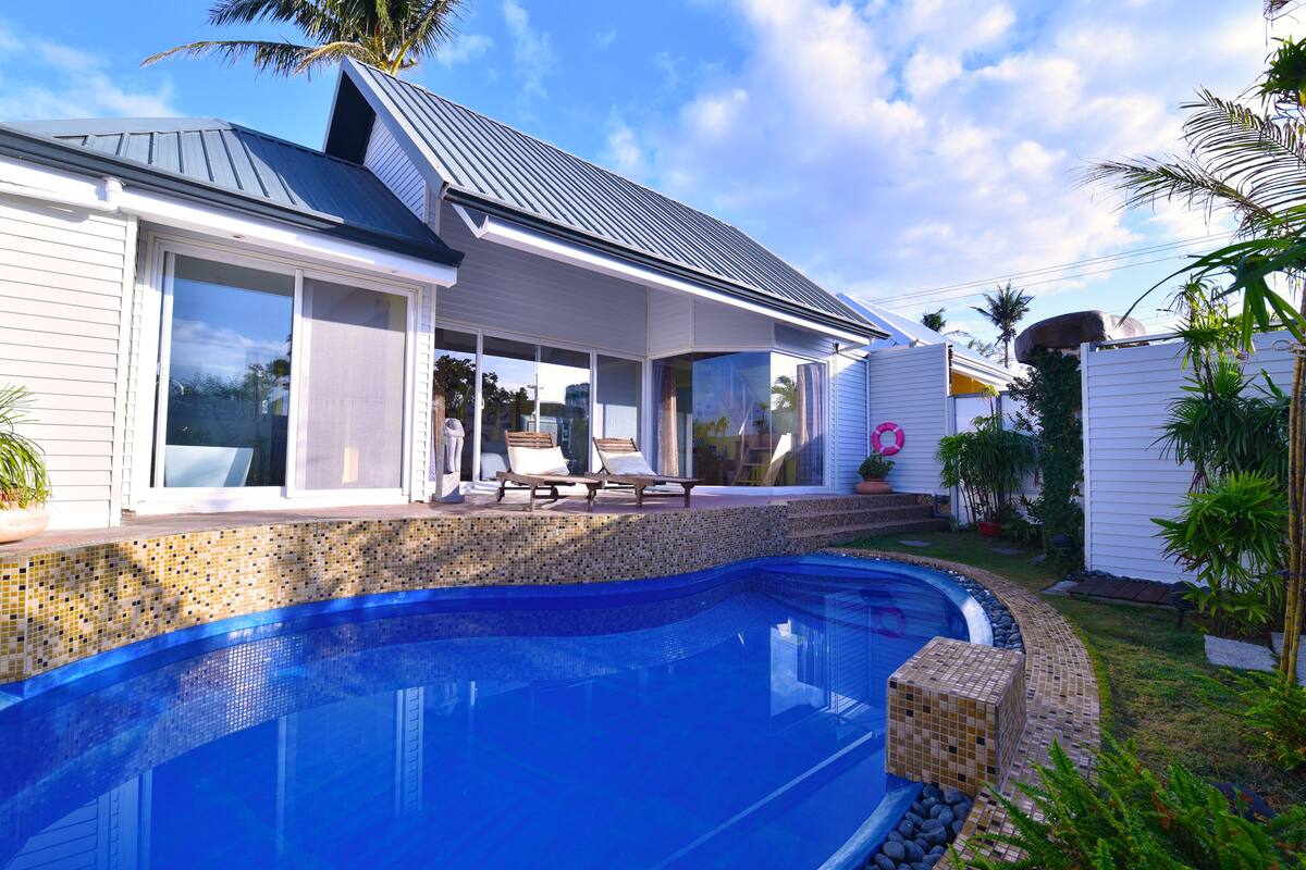 A modern house with a swimming pool, a covered patio, and a garden.