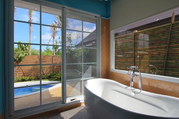 A bathroom with a large window, a bathtub, and a view of a swimming pool and greenery outside. - Kenting Calla Lily Villa (Hengchun)