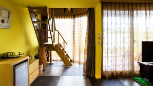 A room with a wooden staircase, a small kitchen area, a television, and a large window with curtains. - Kenting Calla Lily Villa (Hengchun)