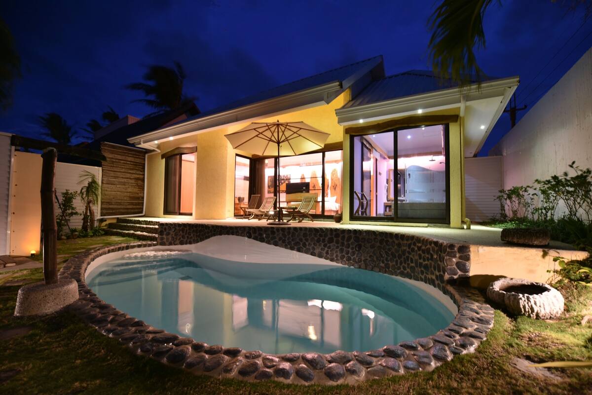 A modern house with a swimming pool, outdoor seating, and a large patio area.