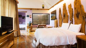 A bedroom with a large bed, a television on a wooden stand, a window with blinds, and a wooden headboard. - Kenting Calla Lily Villa (Hengchun)