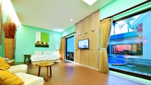 A modern hotel room with a large window, a flat-screen TV, a bed, a sofa, and a small table. - Kenting Calla Lily Villa (Hengchun)