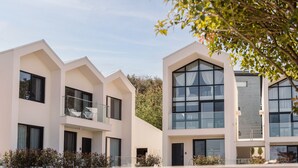 Un moderno edificio residencial de varios pisos, con balcones, ventanas amplias y un diseño de techo plano.