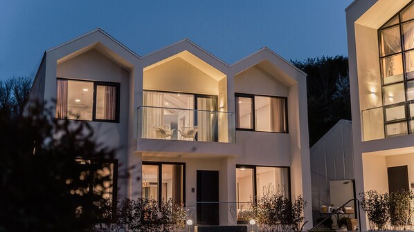 A modern multi-story building with large windows, a balcony, and a well-lit entrance. - Albescent Pool Villa (Gyeongju)