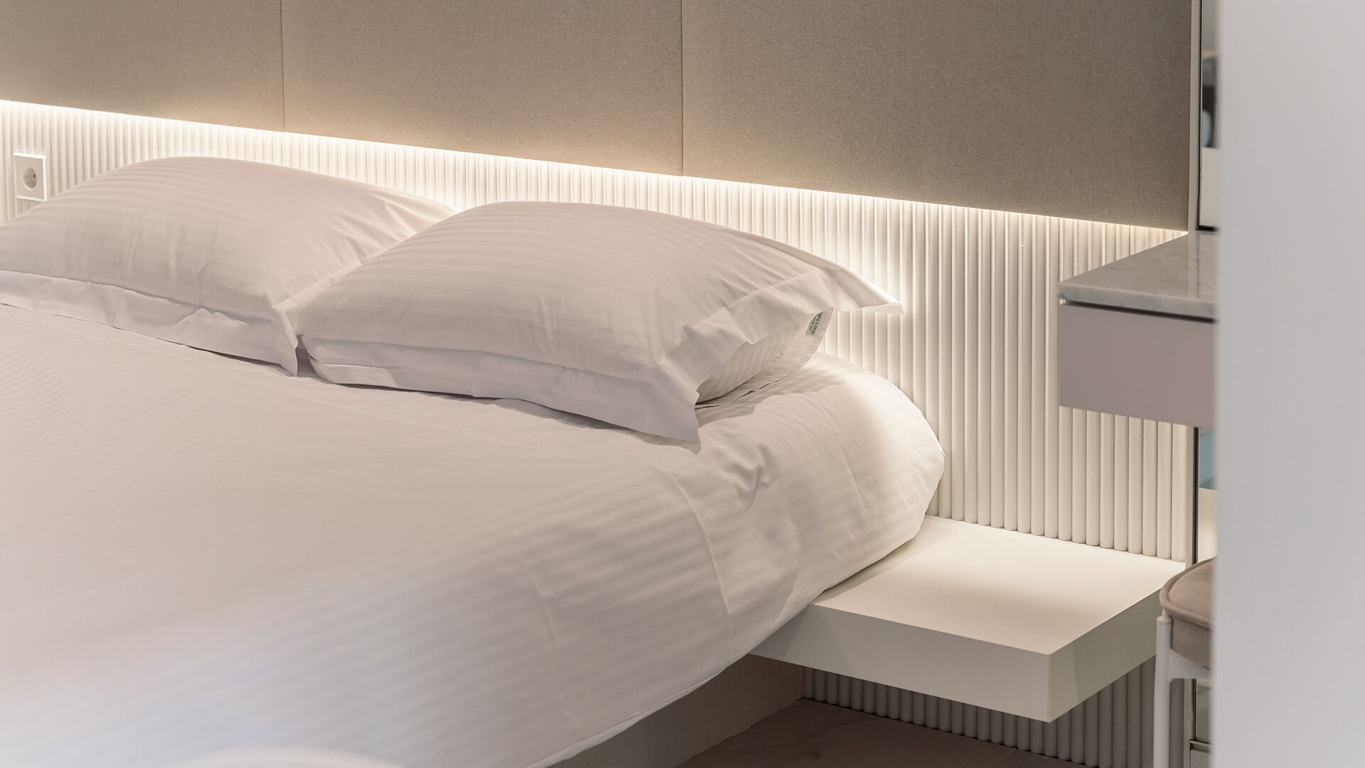 Ein modernes Schlafzimmer mit Bett, Kissen und Nachttisch.