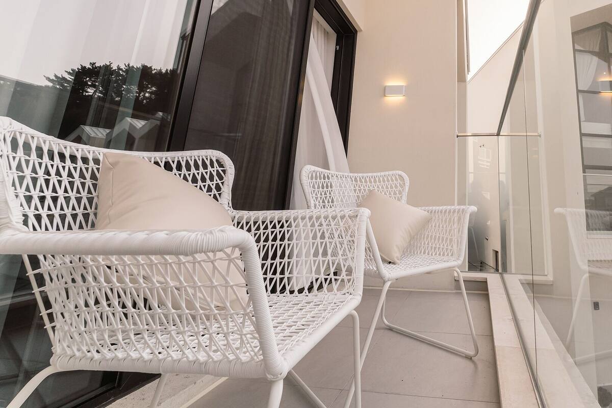 A balcony with white wicker furniture and a glass railing.