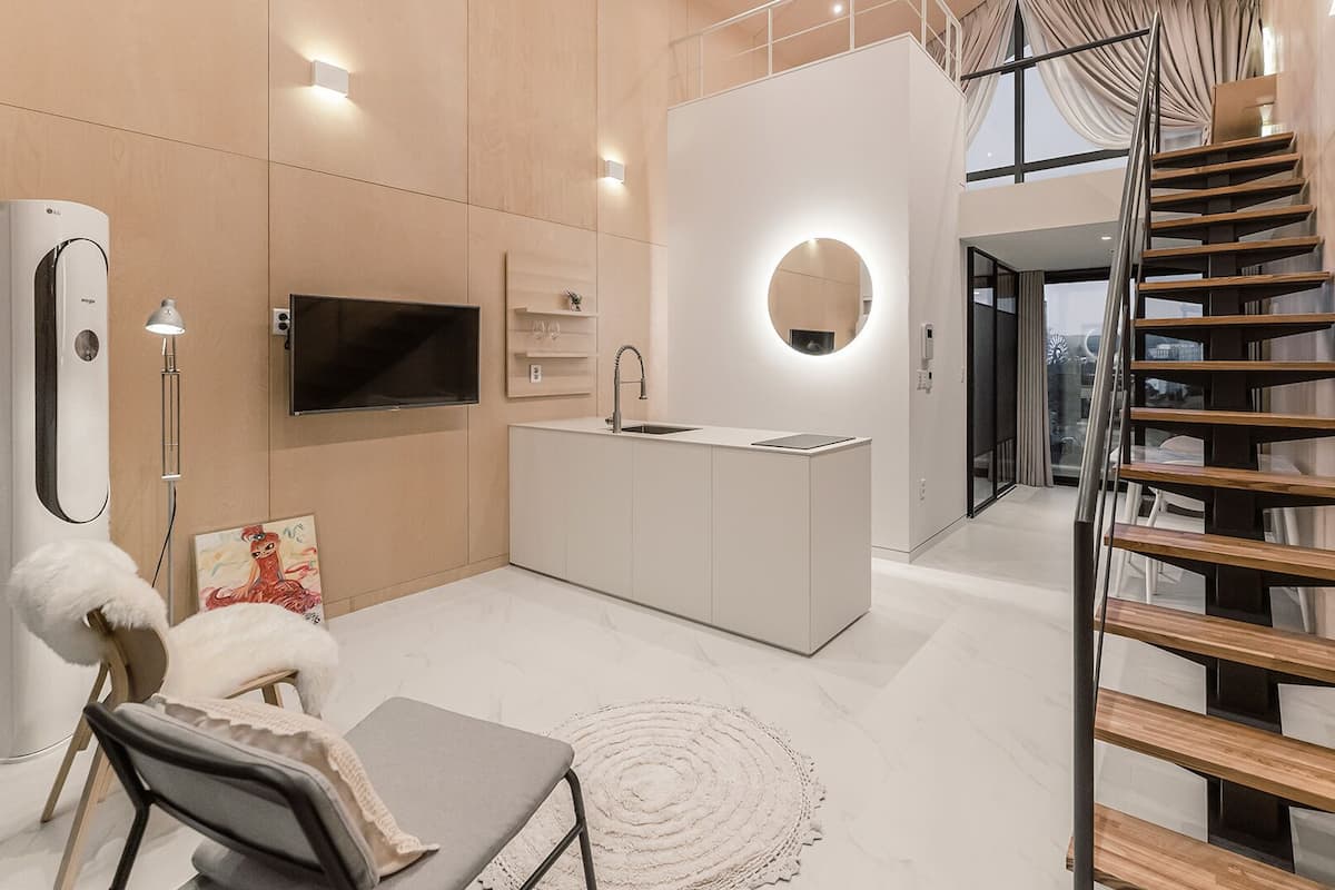 A modern kitchen with a central island, a built-in TV, and a staircase leading to an upper level.