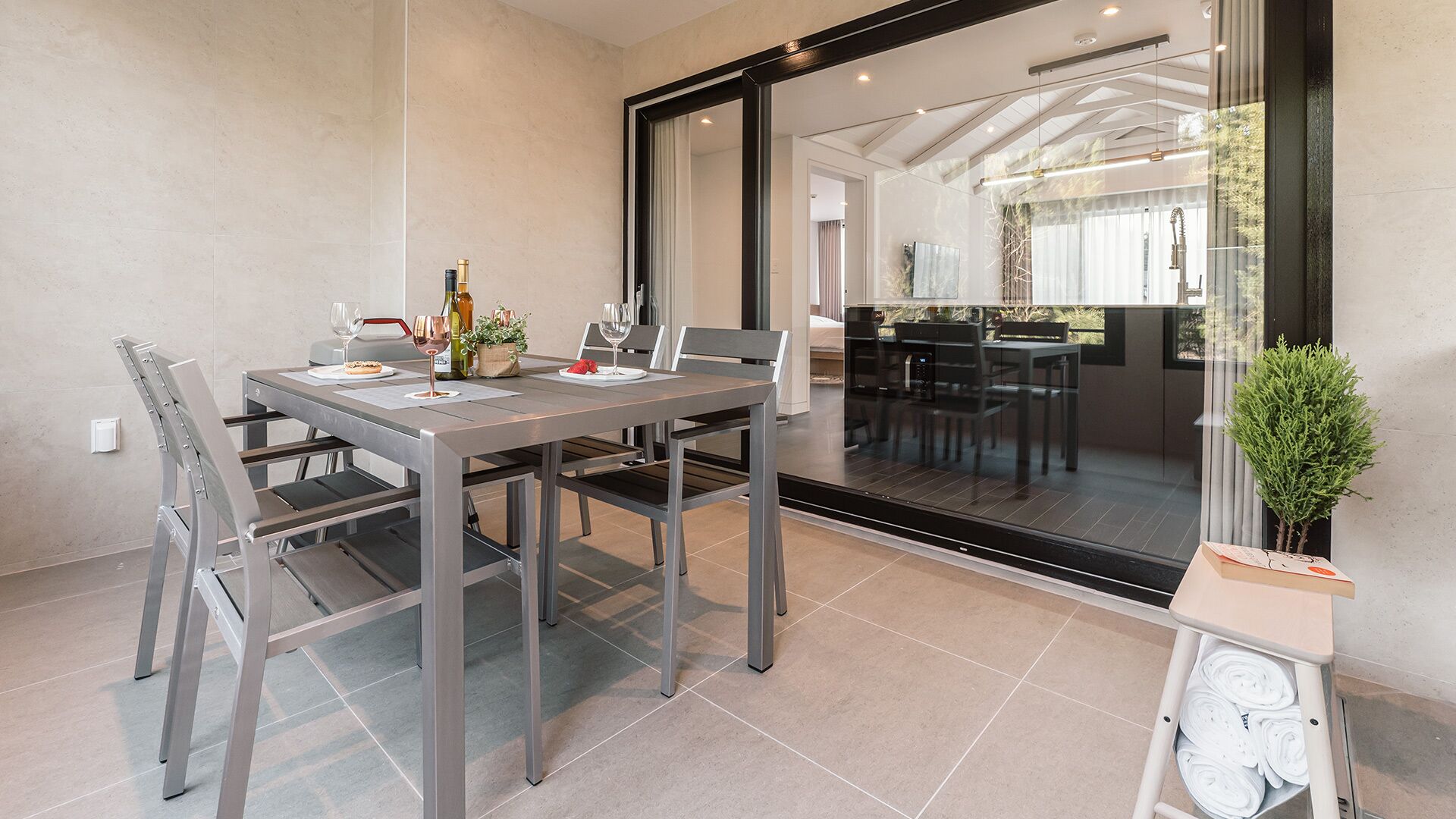 Un comedor moderno con un separador de vidrio, una mesa de comedor con sillas y una pequeña planta en maceta.
