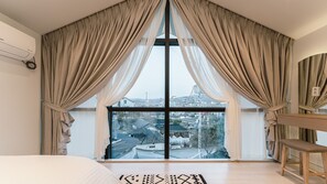 Enjoy a city view from the comfort of this stylish bedroom, featuring a plush bed and a cozy seating area.