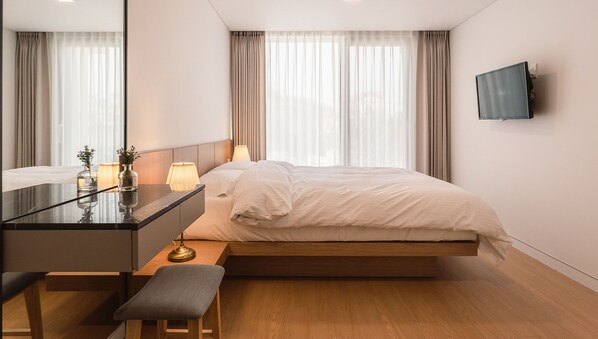 A modern bedroom with a bed, bedside table, lamp, and a TV mounted on the wall. - Albescent Pool Villa (Gyeongju)