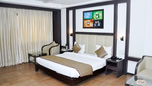 Habitación de hotel con una cama grande, una mesita de noche, una silla y un ventilador de techo.