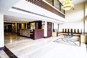 A spacious lobby with a reception desk, seating area, and a chandelier.