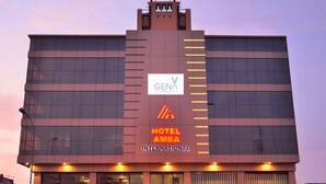 Un edificio moderno con un cartel llamativo que dice "GENA HOTEL AMBA INTERNATIONAL" y la entrada a "CARRY HOUSE RESTAURANT".