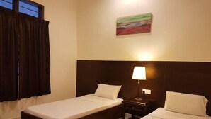 A hotel room with two single beds, a nightstand with a lamp, a painting on the wall, and a window with curtains. - Perhentian Tivoli Inn (Pulau Perhentian Kecil)